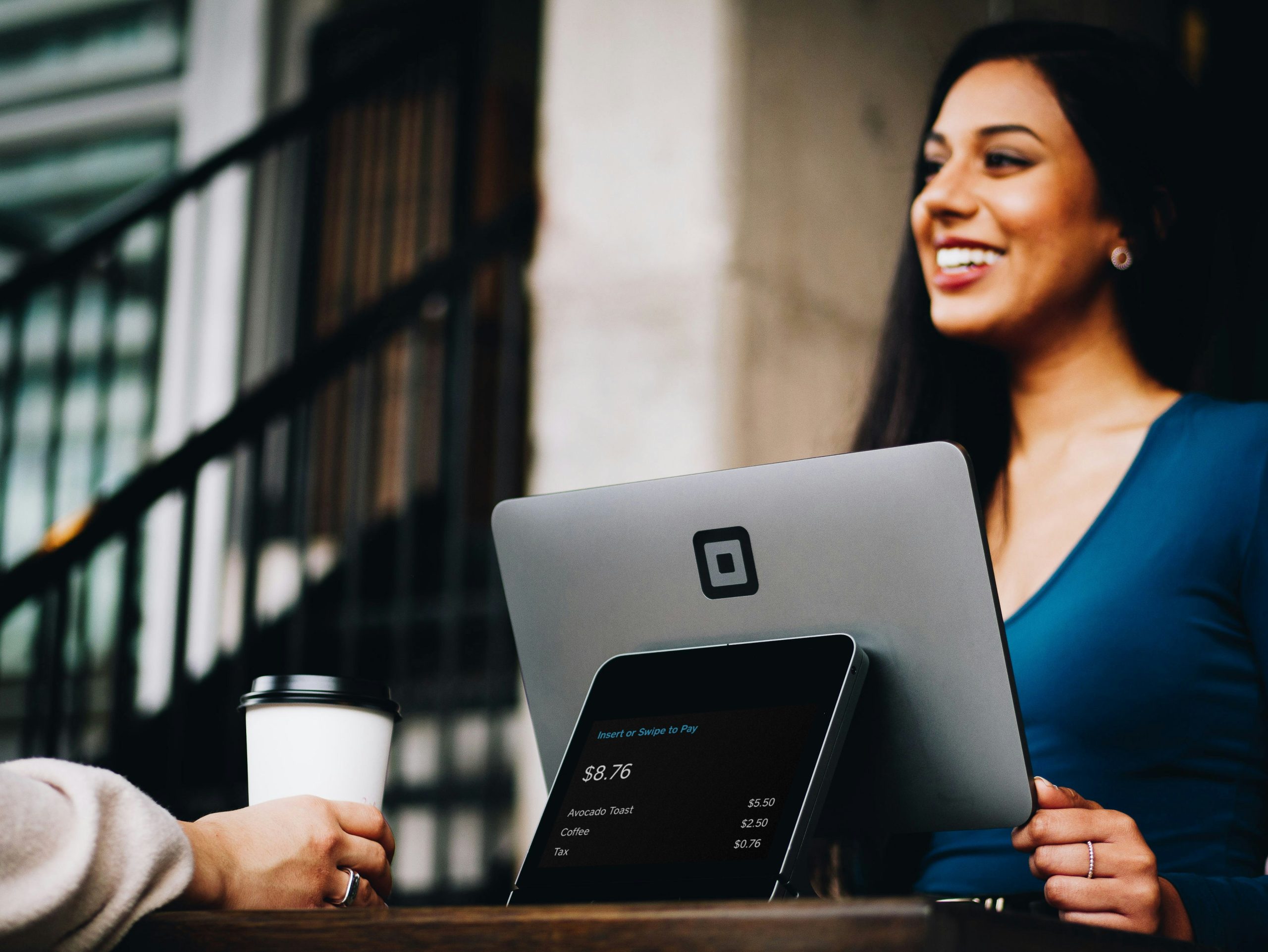 small-medium-ent Woman at a point of sale machine selling coffee to out-of-frame customer